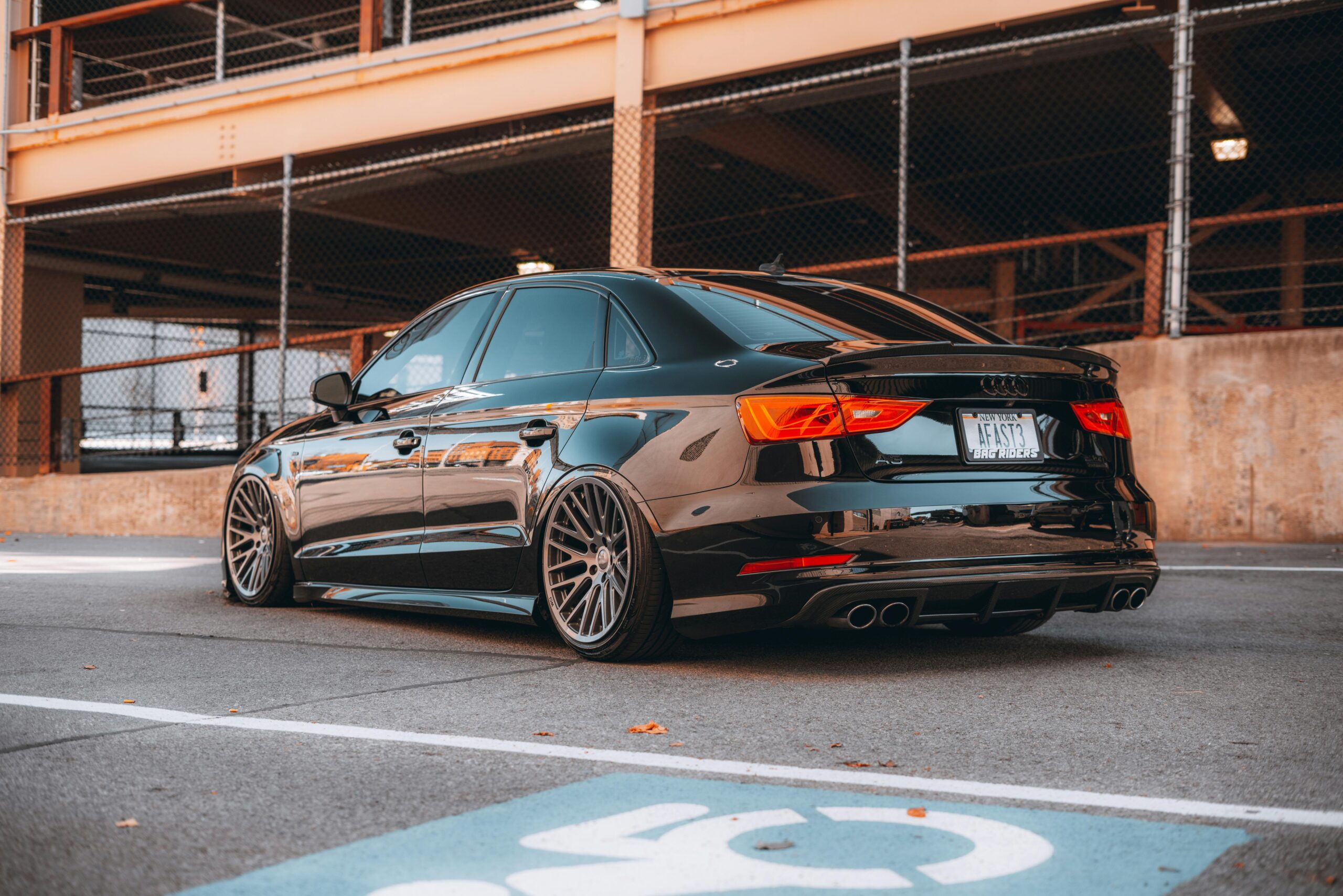 Home Elegant black sedan parked in a city parking lot, showcasing polished design.